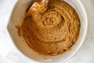 A bowl with the ingredients for pumpkin bread all mixed together.