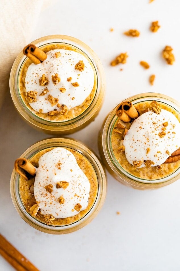 Overhead shot with three jars of pumpkin chia pudding with toppings including whipped coconut topping and granola.