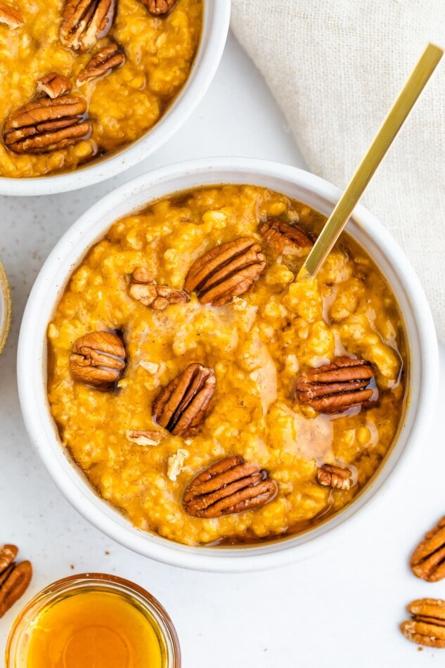 Overhead shot of two bowls of pumpkin oatmeal, one bowl is mostly out of frame.