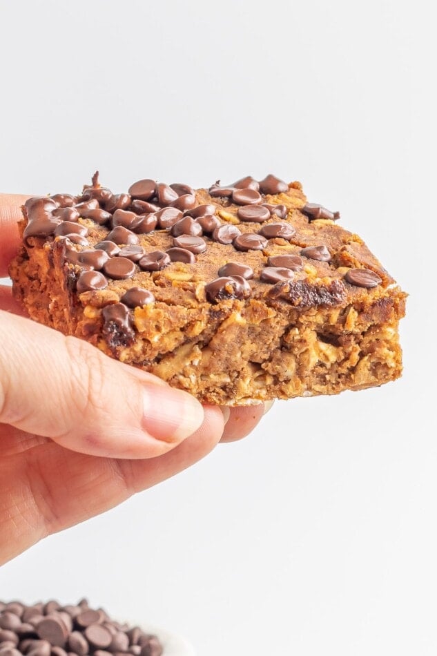 A hand holding up a slice of pumpkin protein bars.