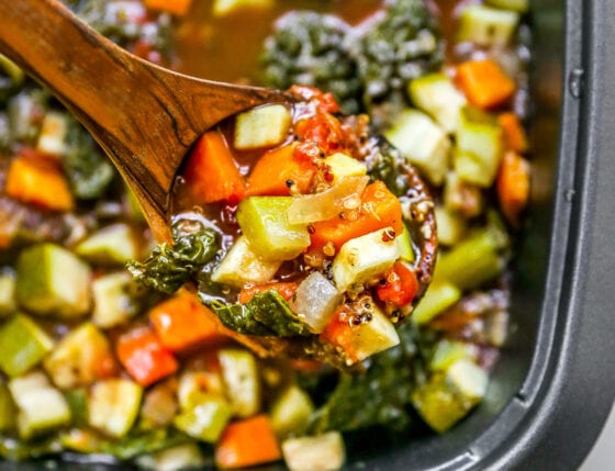 Finished soup in the slow-cooker with a wooden spoon lifting some up.