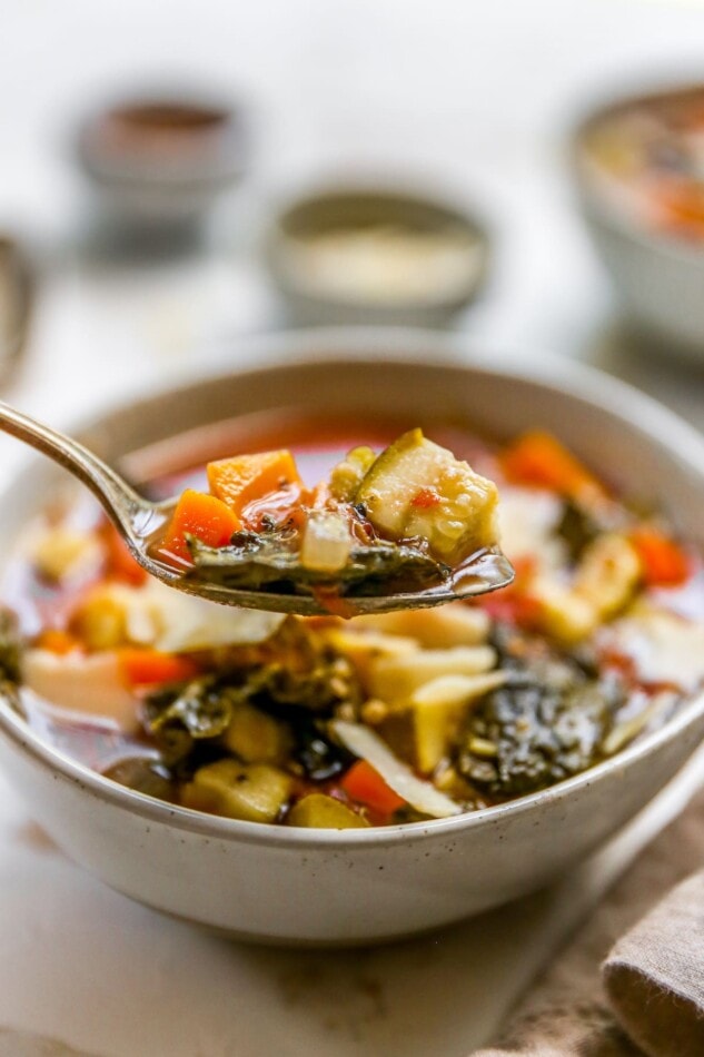 An up close photo of a spoonful of soup with the bowl in the background.