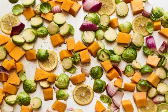 A sheet pan covered with Brussels sprouts, butternut squash, onions, and lemon slices.