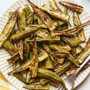 Roasted okra on a plate with a fork.