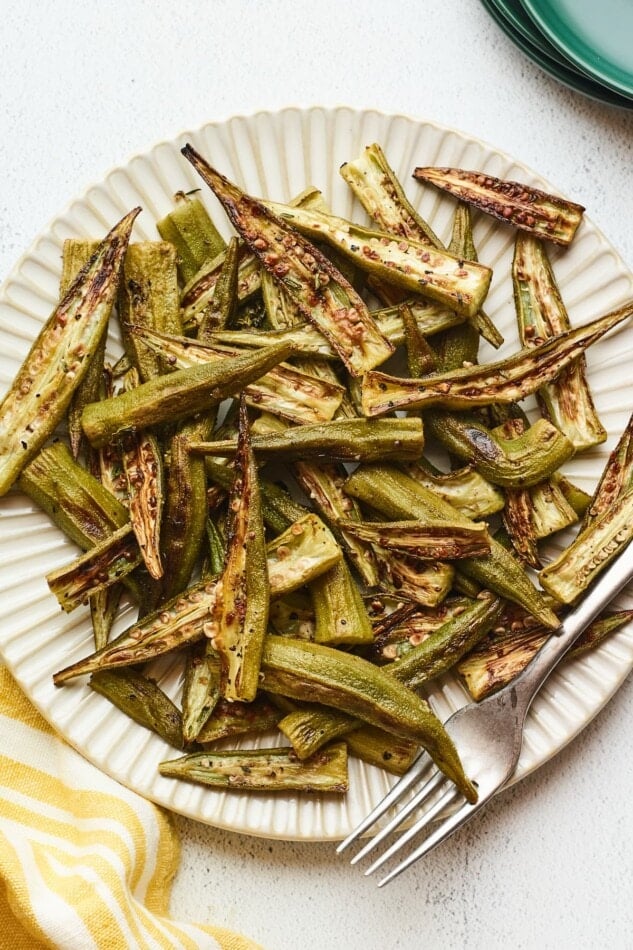 Roasted okra on a plate with a fork.