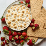 S'mores dip plated with strawberries and graham crackers for dipping.