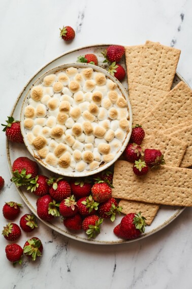 S'mores dip plated with strawberries and graham crackers for dipping.