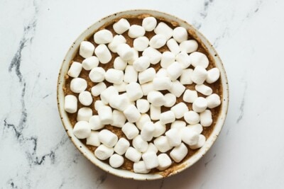Dish of chocolate chickpea s'mores dip topped with mini marshmallows before being baked.