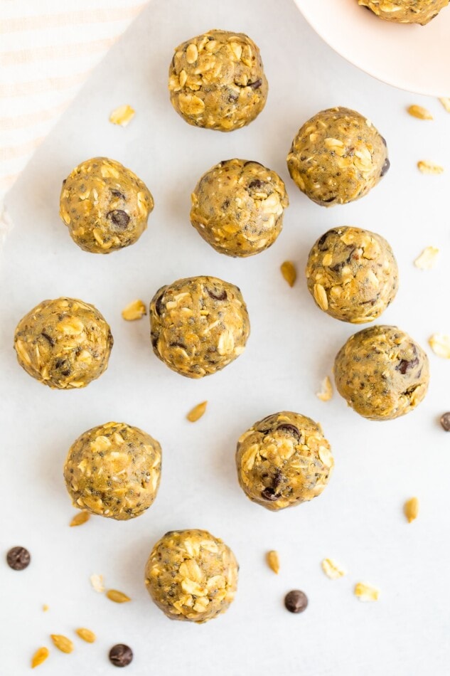 SunButter energy bites laid out on a marble surface with a few oats and chocolate chips scattered around