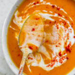 An overhead shot of a spoon ladling out some soup from a bowl.