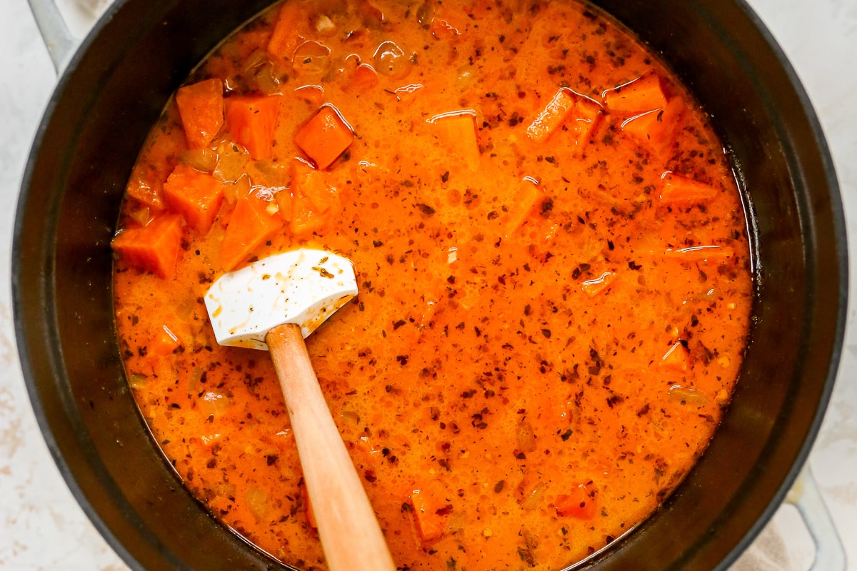 Overhead shot of a pot of soup with a spatula resting inside the pot.