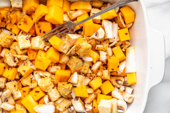 Tamari mixture spread over butternut squash and tempeh in baking dish.