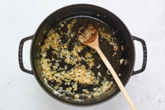 Onions and garlic sauté in a cast iron dutch oven.