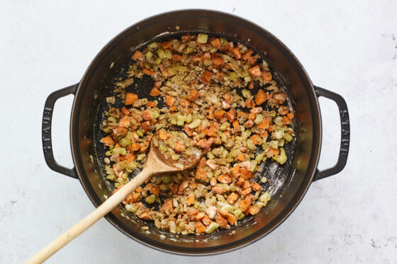 Veggies being coated in flour mixture in cast iron dutch oven.