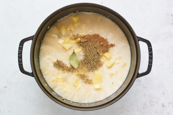 Potatoes, milk, vegetable broth, and seasonings added to the cast iron dutch oven.