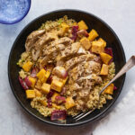 A plate of Za'atar chicken and vegetables over a bed of herbed couscous. A silver fork rests on the plate.