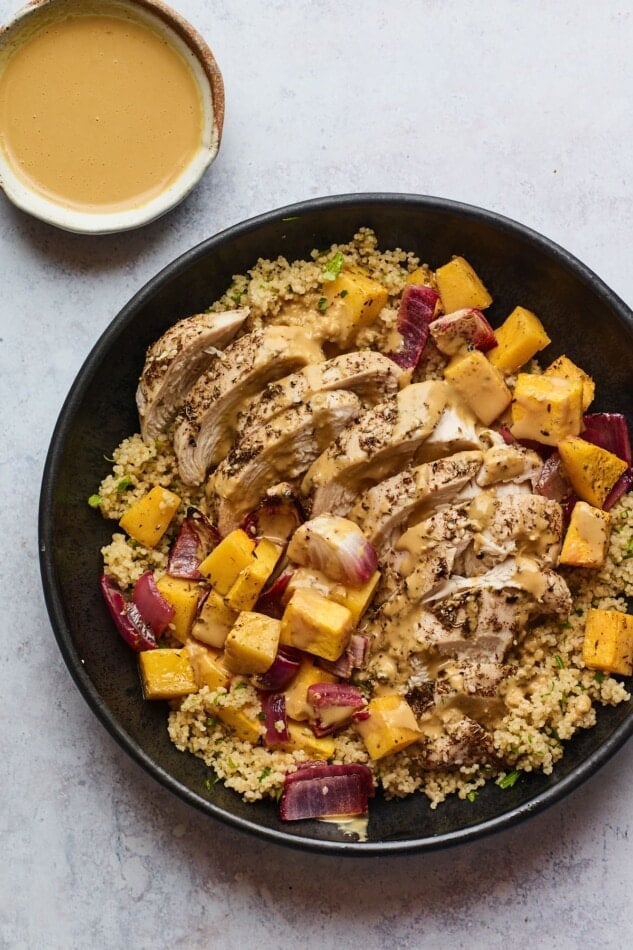 A plate of Za'atar chicken and vegetables over a bed of herbed couscous.