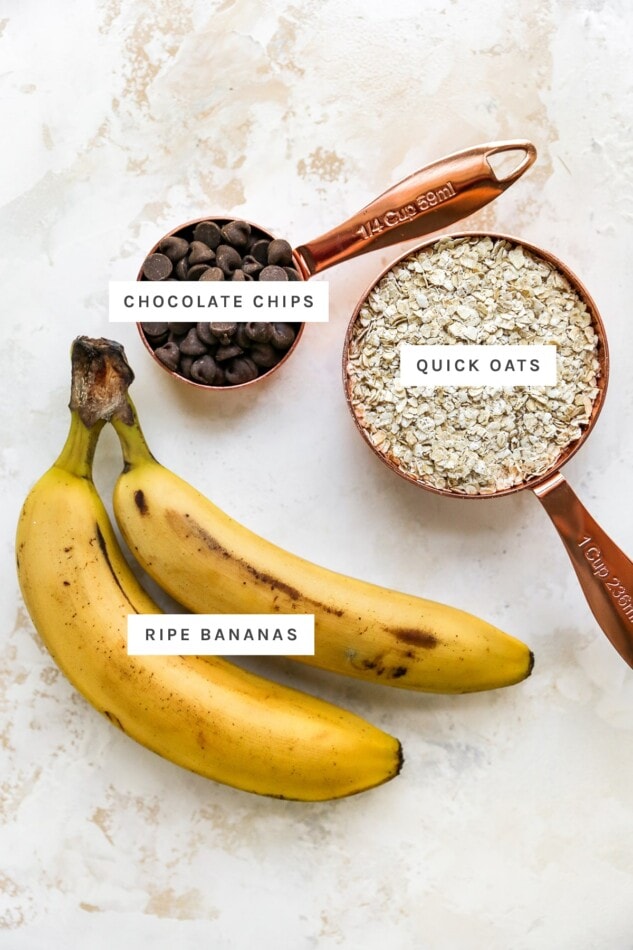 Ingredients measured out to make banana oatmeal cookies: chocolate chips, quick oats and ripe bananas.