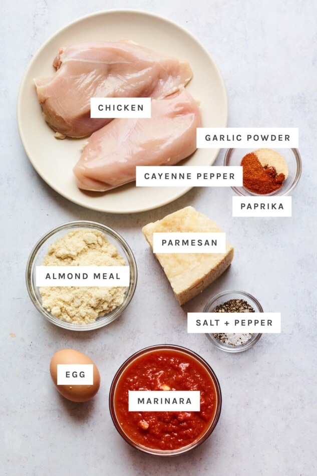 Ingredients measured out to make chicken parmesan: chicken, garlic powder, cayenne pepper, paprika, almond meal, parmesan, salt, pepper, egg and marinara.