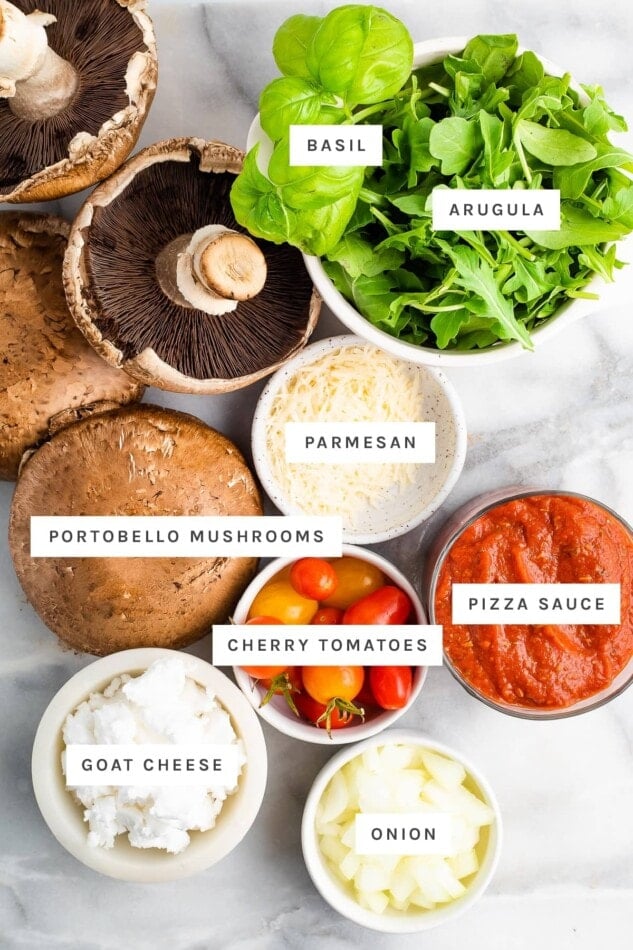 Ingredients measured out to make portobello pizzas: basil, arugula, parmesan, portobello mushrooms, pizza sauce, cheery tomatoes, goat cheese and onion.