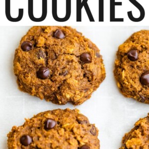 A close up of pumpkin oatmeal cookies, fresh from the oven. The cookies are resting on a sheet of parchment paper.