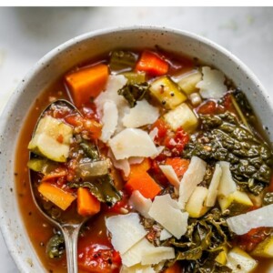 Overhead shot of quinoa vegetable soup with a spoon lifting some soup out of the bowl.