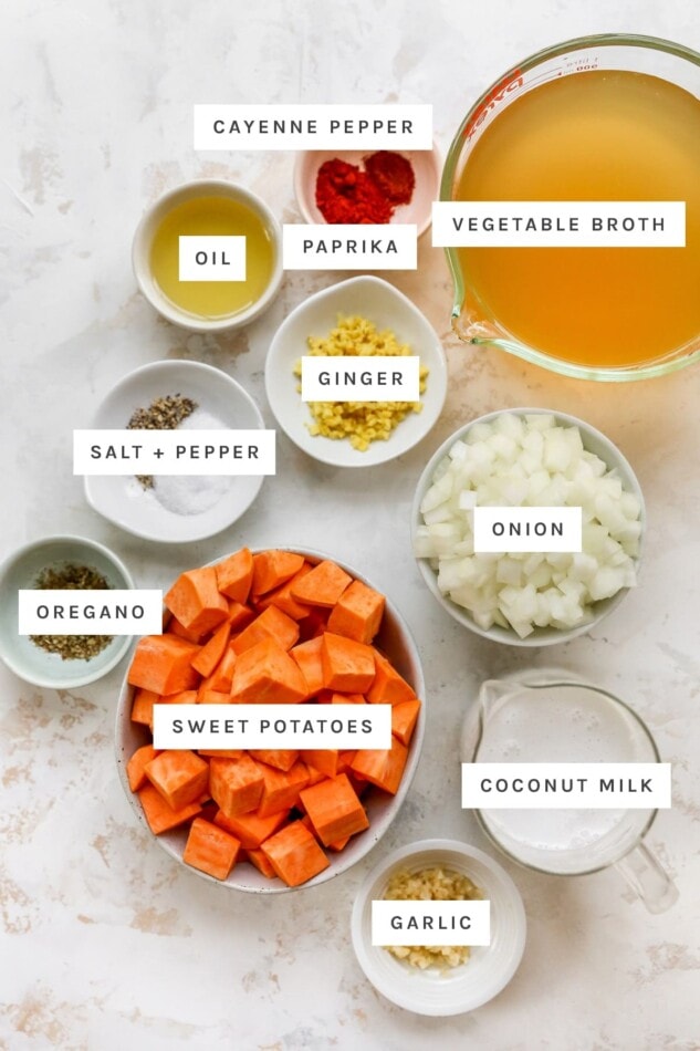 Ingredients measured out to make sweet potato soup: cayenne pepper, vegetable broth, oil, paprika, ginger, salt, pepper, onion, oregano, sweet potatoes, coconut milk and garlic.