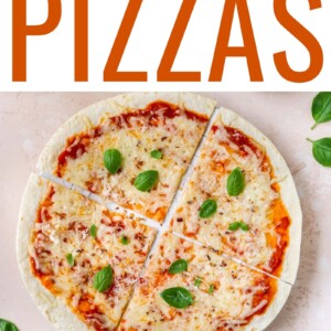 A close up overhead shot of a tortilla pizza. A ramekin of cheese is in the bottom right corner of the image. Basil is on the table as well.