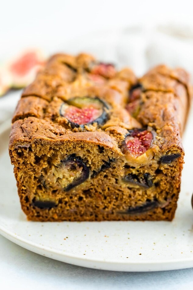 A loaf of sliced fig bread on a plate. You can see the figs inside the bread.