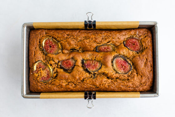 A cooked loaf of fig bread, still inside the bread baking pan.