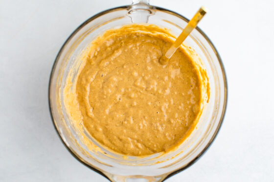 Dry ingredients incorporated into wet ingredients with a gold spoon sticking out of the bowl.