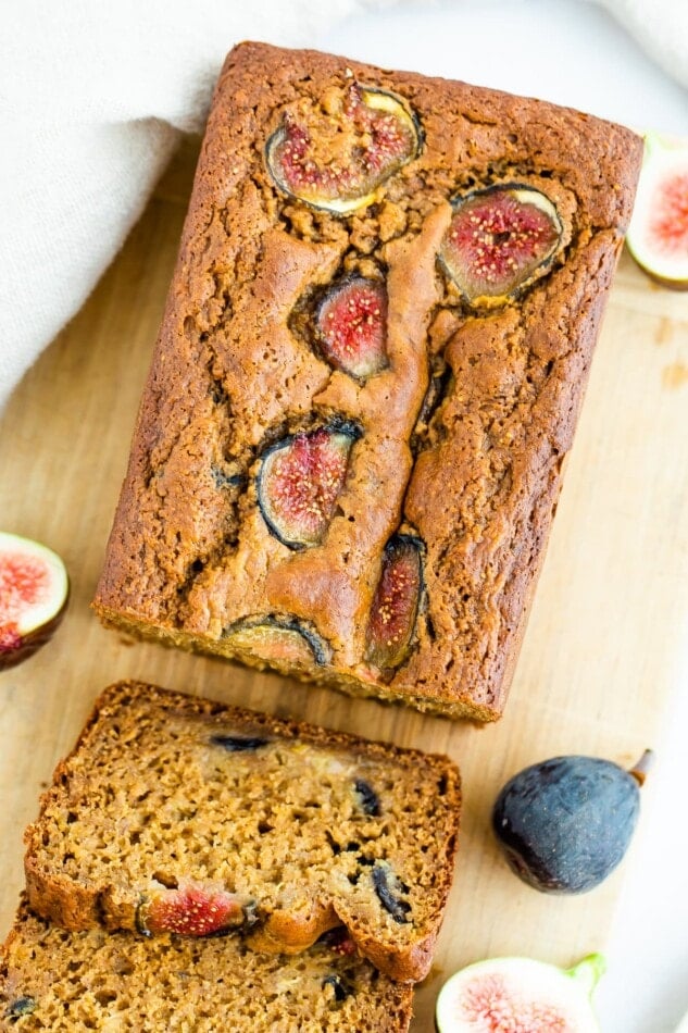 Overhead and close up shot of fig bread, with fig slices on top. There are two slices of fig bread to the side.