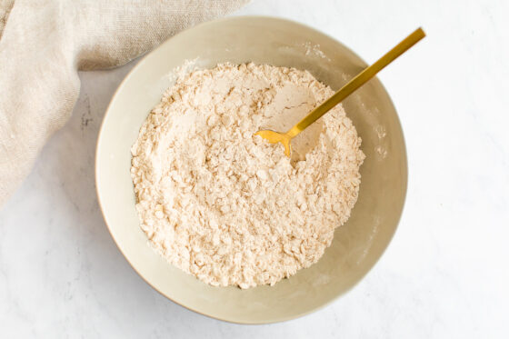 Dry ingredients mixed together with a golden spoon inside a bowl.