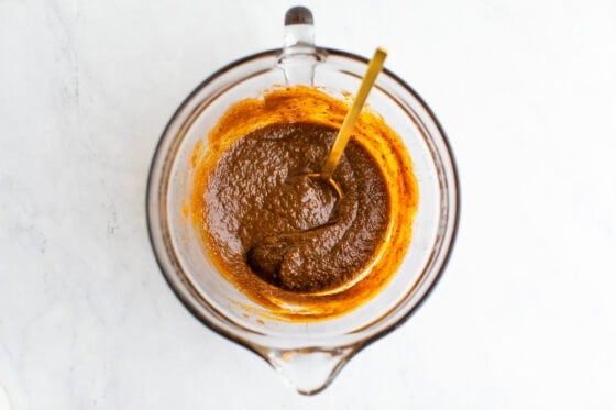 Wet ingredients mixed together in a mixing bowl with a golden spoon resting inside the bowl.