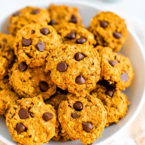 A white bowl filled with pumpkin oatmeal cookies.