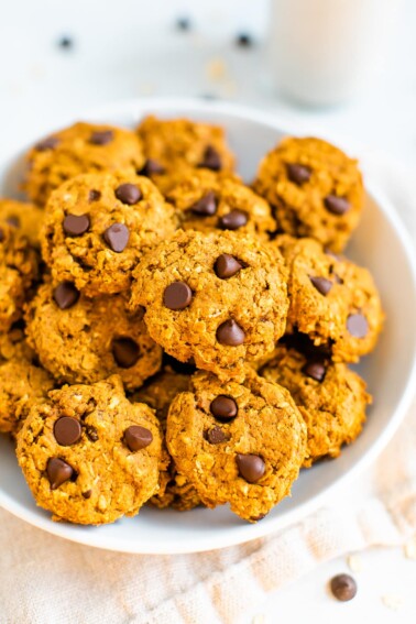 A white bowl filled with pumpkin oatmeal cookies.