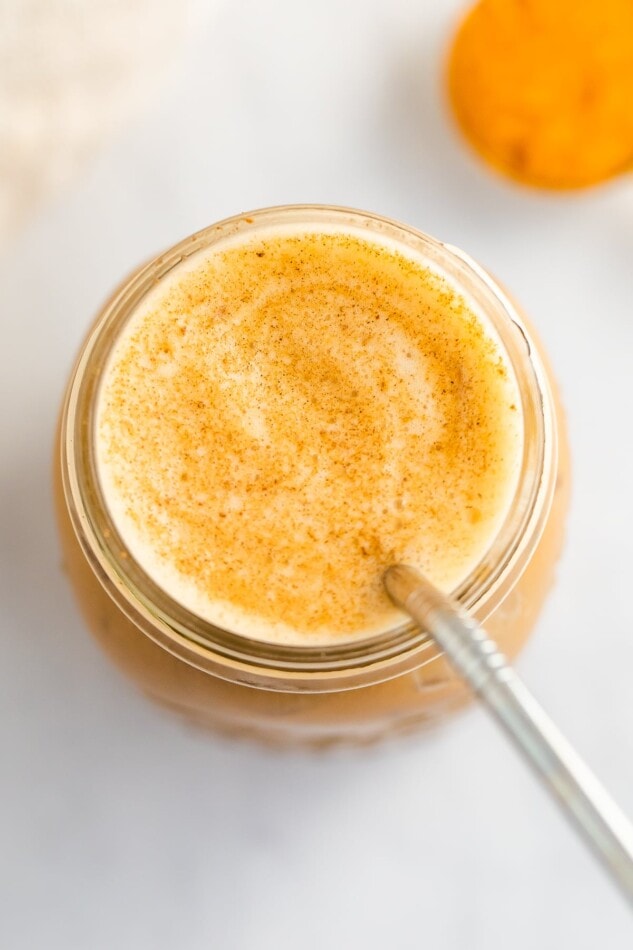 An overhead shot of a mason jar filled with pumpkin cream cold brew, sprinkled with pumpkin pie spice on top.