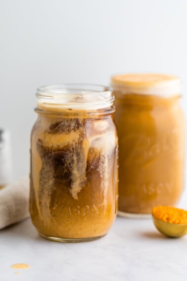 A jar of pumpkin cream cold brew with a second jar out of focus in the background.