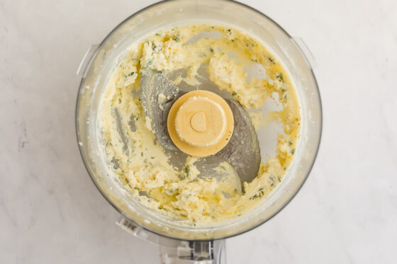 A food processor with freshly whipped ricotta and fresh thyme.