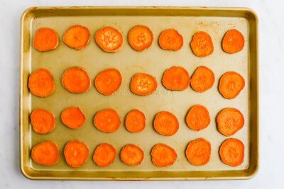 A sheet pan with 4x7 baked sweet potato rounds spread across it.