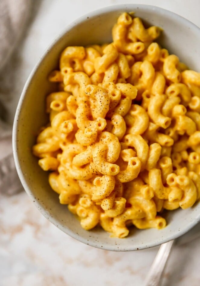 Overhead closeup photo of a bowl of vegan mac and cheese sprinkled with pepper.