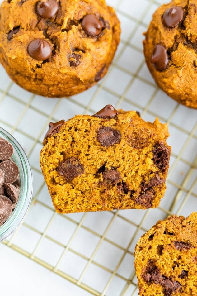 A muffin cut in half, resting on a wire rack, exposing the inside. There are additional muffins resting on the wire rack.