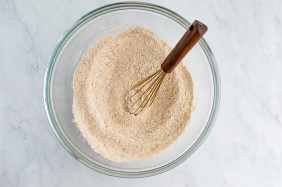 A glass mixing bowl with dry ingredients mixed together.