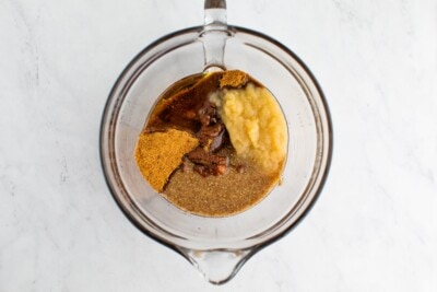 A glass mixing bowl with wet ingredients for vegan pumpkin muffins, ready to be mixed together.