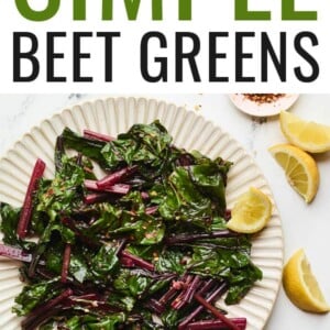 A plate of beet greens with a few lemon wedges and red pepper flakes.