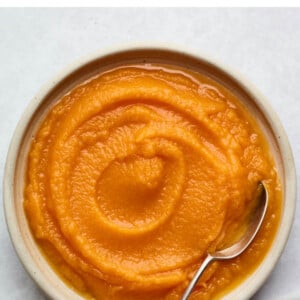 Bowl of butternut squash puree with a spoon in it.