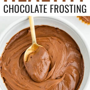 An overhead photo of a bowl of health chocolate frosting. A gold spoon rests inside of the bowl with a scoop of frosting on top of it.