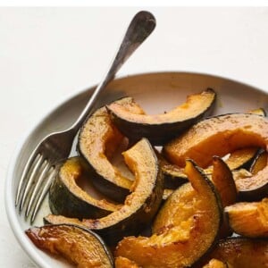 Plate with cinnamon maple roasted kabocha squash. Serving fork is on the bowl as well.