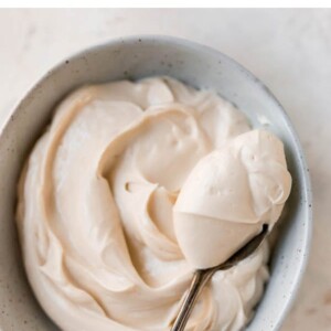 Bowl of cream cheese frosting with a spoon.