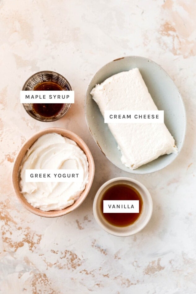 Ingredients measured out to make healthy cream cheese frosting: maple syrup, cream cheese, greek yogurt and vanilla.